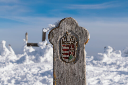Hungarian crest on an old cross on a snowy hilltop