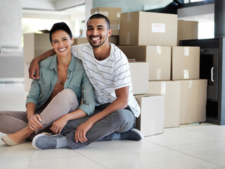 All the boxes are in, time to start unpacking. Portrait of a happy young couple sitting on their...