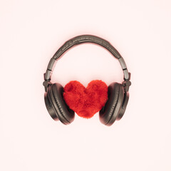 Fluffy soft heart with black headphones on white background. Feelings, love and emotions. Music and sound. Flat lay.