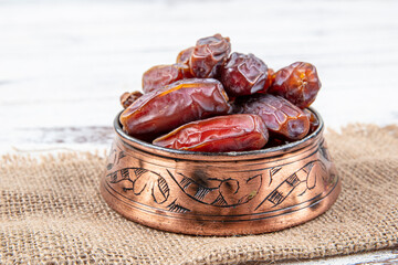Plate of dates on a white wooden background. Dried date fruits or kurma, ramadan (ramadan) food.