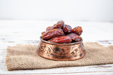 Plate of dates on a white wooden background. Dried date fruits or kurma, ramadan (ramadan) food. - obrazy, fototapety, plakaty