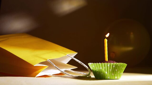 Single yellow birthday candle on a cupcake 