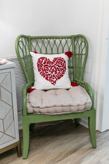 A green interior house chair with a heart decoraitive pillow