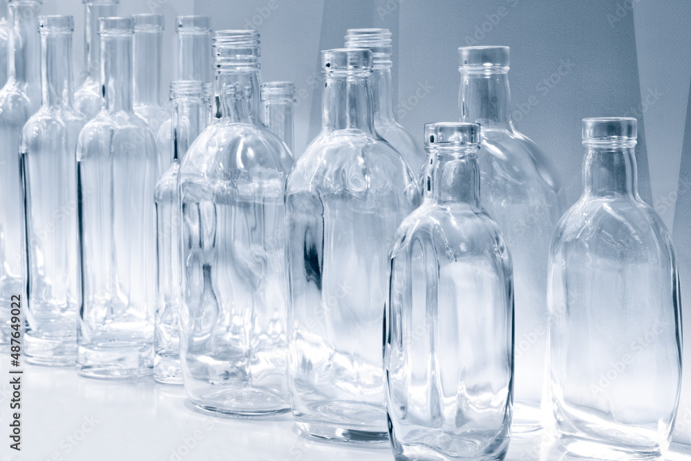 Poster empty glass bottles in a row on a shelf in blue tone, isolated on white background