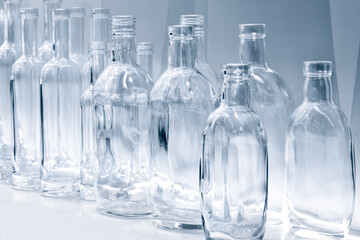 Empty glass bottles in a row on a shelf in blue tone, isolated on white background