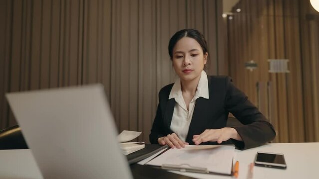 Asian Concentrated Young Entrepreneur Woman In Formalwear Late Working Alone At Office Room. Closeup Focused Executive CEO Signing Report After Checking Information. Business And Succession