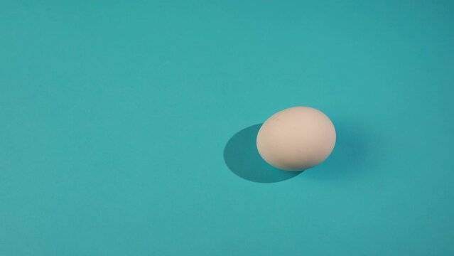Easter egg are spinning turning on blue table. Egg trendy colored classic blue, white and golden . Happy Easter. Minimal style. Top view.