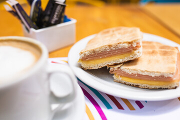 coffee next to toasted ham and cheese sandwiches