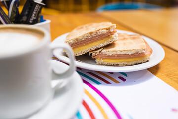 coffee next to toasted ham and cheese sandwiches