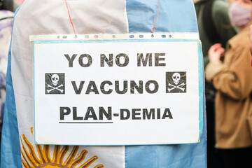 Unrecognizable person carrying an Argentinean flag and an anti-vaccine sign