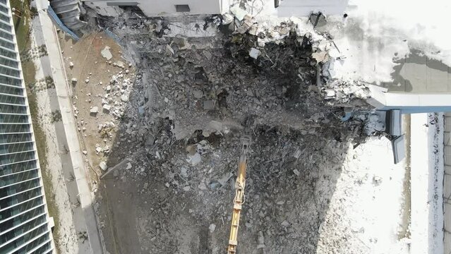 Excavator with Hydraulic Shears in action, Aerial view of building demolition. Slow Motion of Heavy machinery destroying a building