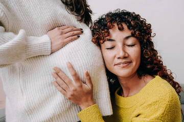 LGBT lesbian pregnant woman having tender moment listening her wife baby belly - Focus on right...