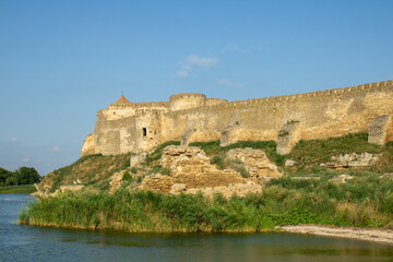 Fototapeta na wymiar View of the defensive medieval fortress from the sea against the blue sky. Ancient citadel and towers of the fortress walls. Archaeological excavations of the historical bastion Akkerman.