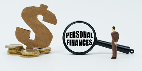 On a white surface, a dollar symbol, a human figure and a magnifying glass with the inscription - Personal Finances