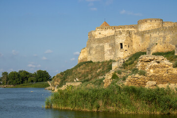 Fototapeta na wymiar View of the defensive medieval fortress from the sea against the blue sky. Ancient citadel and towers of the fortress walls. Archaeological excavations of the historical bastion Akkerman.