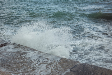Wave crashes on the concrete embankment, the sea is stormy
