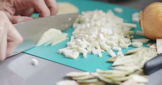 Cooking at home, celery root chopping using kitchen knife, close-up