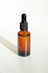 Bottle with dropper pipette with serum or essential oil. White background with daylight. Skincare products , natural cosmetic. Beauty concept for face and body care