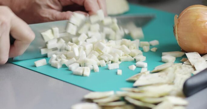 Cooking at home, celery root chopping using kitchen knife, close-up