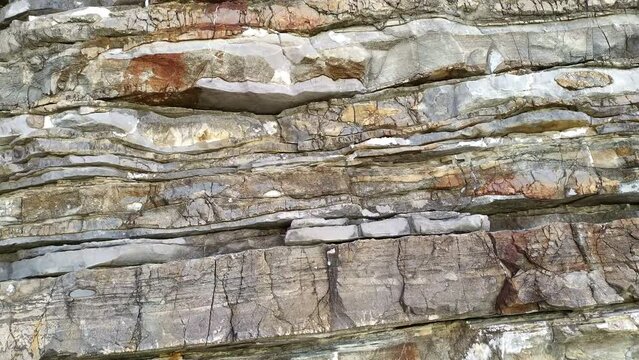 Cliff - rugged dipping sedimentary rock mountain formation. Vertical natural rough wall of stratum layers, jagged, sliced and cracked. Geological strata canyon.