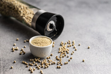 White ground pepper and whole peppercorn spice in bowl.