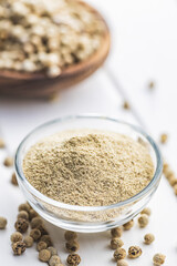 White ground pepper and whole peppercorn spice in bowl.