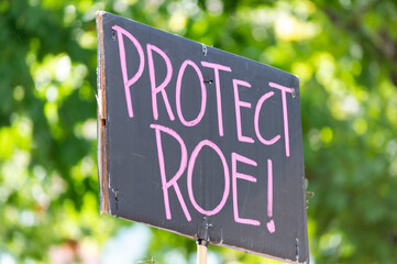 A hand holding a sign supporting protecting Roe v. Wade during a planned parenthood rally for...