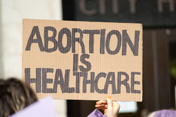 A hand holding a sign supporting pro-choice abortion laws during a planned parenthood rally for abortion justice.