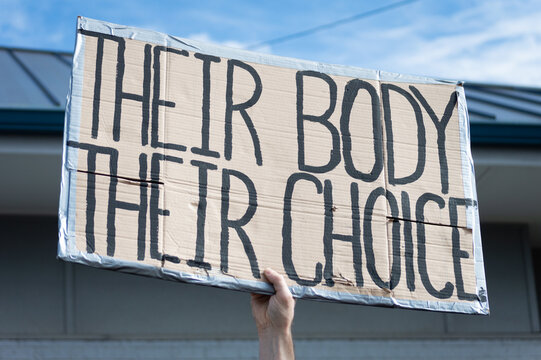A hand holding a sign supporting pro-choice during a planned parenthood rally for abortion justice.