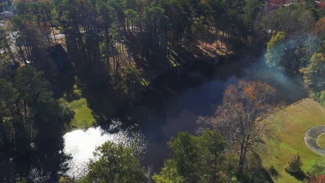 Aerial drone fly over of small lake with a glimpse of sun.