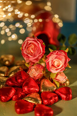 Heart shaped chocolates. Bouquet of silk pink, red roses and dark blue background with yellow bokeh. Copy space.