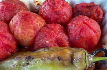 Baked and peeled tomatoes in a plate with other vegetables