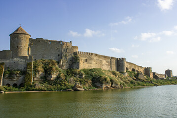 Fototapeta na wymiar View of the defensive medieval fortress from the sea against the blue sky. Ancient citadel and towers of the fortress walls. Archaeological excavations of the historical bastion Akkerman.