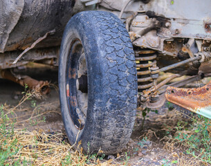 Fototapeta na wymiar The front suspension and the hub of an abandoned rusty retro car in a web. 