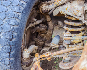 The front suspension and the hub of an abandoned rusty retro car in a web.