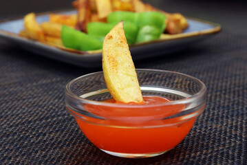 A piece of french fries left in a container with ketchup on a blurred background. Close-up