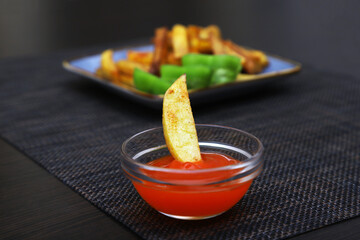 A piece of french fries left in a container with ketchup on a blurred background. shallow depth of field