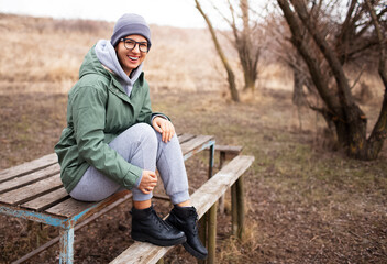 Fototapeta premium Portrait of young smiling woman, sitting on the bench in the park zone.