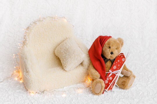 Shoot set up with sofa, teddy bear and garland for newborn on white background. Photo zone for a photo session of newborns. Setup ready for newborn photo shoot and baby photography. Winter fantasy 