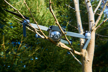 Drone quadcopter accident scene. UAV Quadrocopter crashed on tree in forest. Drone quadcopter accident scene. Destroyed expensive drone hanging in the branches of spruce