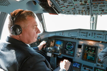 Male pilot sitting in cockpit of passenger airplane