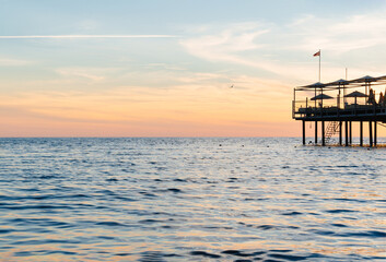 beautiful sunset on the sea. pier with umbrellas and sunbeds for vacationers