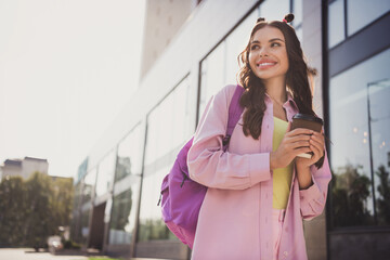 Fototapeta premium Portrait of attractive cheerful dreamy wavy-haired girl drinking latte spending time strolling on fresh air outdoors