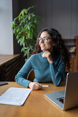 Fototapeta premium Confident lecturer woman relaxed look in window after online class, lecture or training. Successful businesswoman in eyeglasses sit at office desk with laptop and business papers happy and satisfied