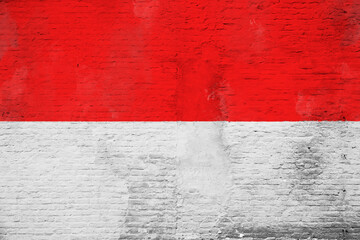 Full frame photo of a weathered flag of Indonesia painted on a plastered brick wall.