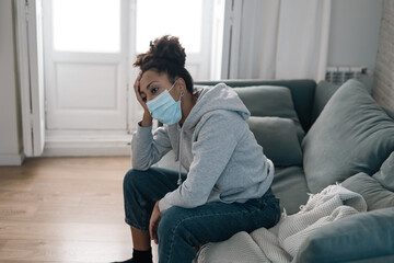 Young black woman wearing protective mask against COVID virus suffering from depression