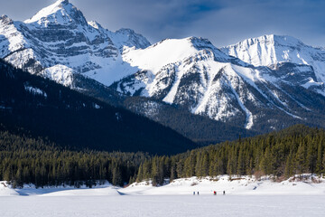 People snow shoeing across a snow covered meadow in the Canadian Rocky Mountains neat Banff Canada.