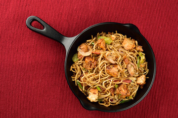 top view of chicken noodles in pan on placemat 