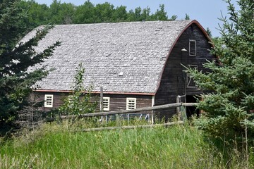 an old wooden barn is surrounded by a split rail fence