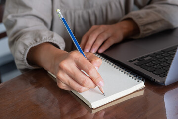 a girl's hand writes in a notebook, a laptop rests on the desk, a freelancer is at work. High-quality photo